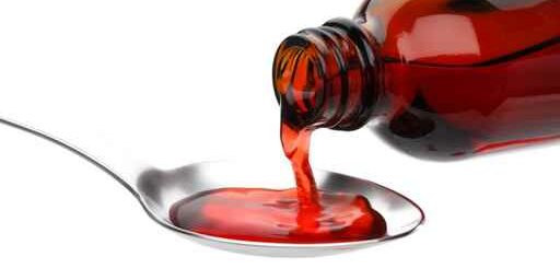 Bottle pouring Medicine Syrup in Spoon